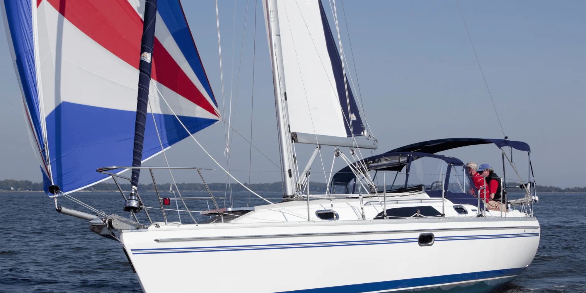 A Catalina 355 under a striped spinnaker, two sailors in her cockpit
