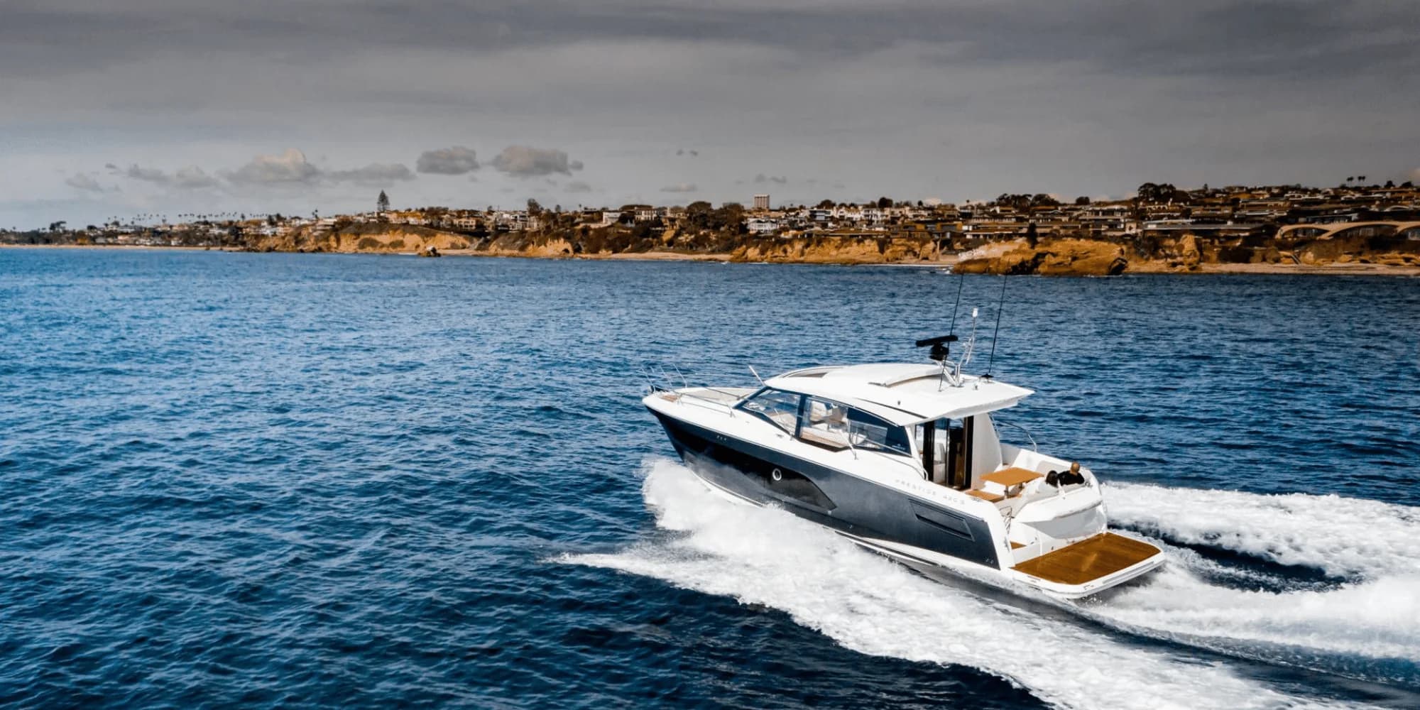 A Prestige 420S running along a rocky coastline
